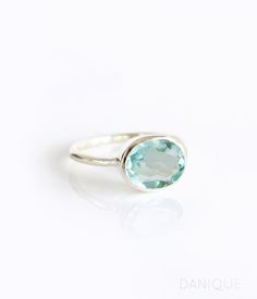 a ring with an oval cut aqua blue topazte in the center on a white background