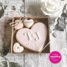 a heart shaped cookie in a box next to a white rose