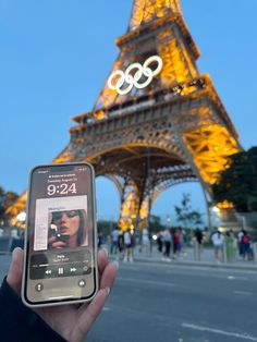 someone holding up their cell phone in front of the eiffel tower