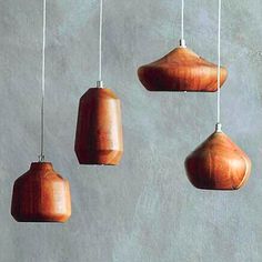 five wooden ornaments hanging from strings on a wall