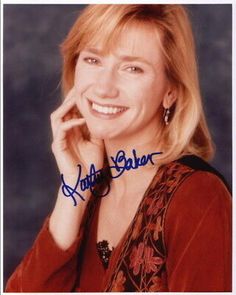 a woman with blonde hair smiling at the camera and holding her hand to her face