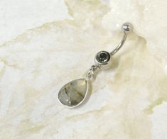 Labradorite Belly Button Ring Perfect for showing off your beautiful belly! Belly ring features a silver plated faceted labradorite gemstone teardrop that dangles from a 14g surgical steel barbell with your choice of clear crystal gem or black diamond gem. Labradorite stone measures 10 x 14mm. Belly button ring measures 1 3/4 inches long total length. Barbell is 14g surgical steel. Top ball measures 5mm, bottom ball measure 8mm. For Belly Button Rings: https://www.etsy.com/shop/AllAboutClass?sec Belly Button Rings Silver, Belly Button Jewellery, Silver Teardrop Belly Rings For Gifts, Belly Button Rings Dangle, Ring Teardrop, Titanium Belly Ring, Bellybutton Piercings, Belly Button Jewelry, Dangle Belly Rings