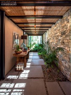 the inside of a house with stone walls and plants on either side of the walkway