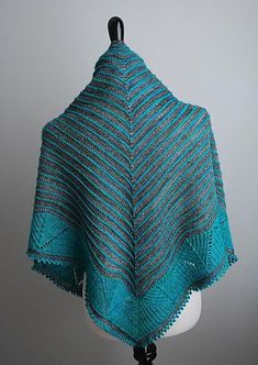 a blue knitted shawl draped over a white mannequin