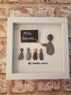 a white frame with some rocks in it and a sign that says miss davies