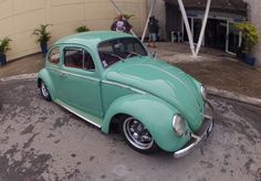 an old green car parked in front of a building