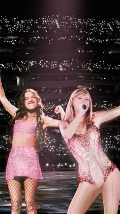 two women are performing on stage with their arms in the air