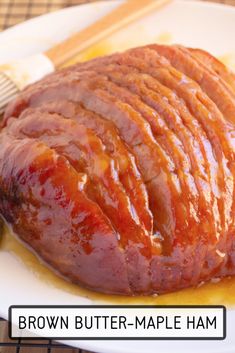 a piece of meat sitting on top of a white plate next to a wooden spatula