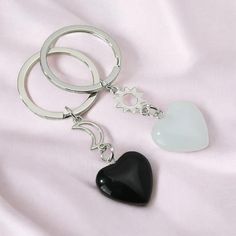 a heart shaped keychain sitting on top of a white sheet next to a black heart