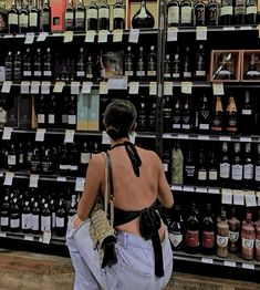 a woman standing in front of a display of wine bottles and other liquors at a store