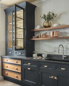 a kitchen with black cabinets and marble counter tops, gold pulls on the doors and brass knobs