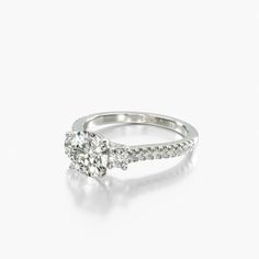 a diamond engagement ring with diamonds on the band and an oval shaped center stone in white gold