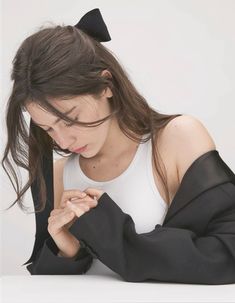 a woman with long hair wearing a white top and black bow tie around her neck