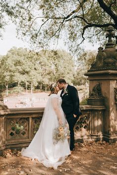 a bride and groom kissing in the park