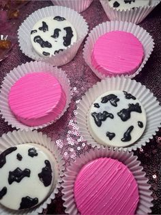 cupcakes decorated with pink and black icing are sitting on a purple tablecloth