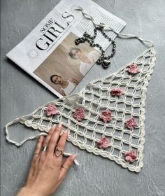 a woman's hand is touching the crocheted triangle on top of a magazine