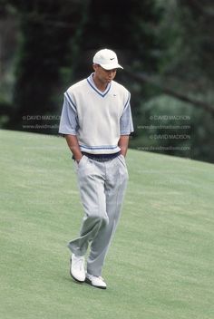 a man standing on top of a green field next to a golf ball in his hand