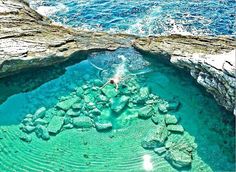 a person swimming in the ocean near rocks and water with green algae growing on them