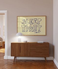 a living room with a large poster on the wall next to a wooden sideboard