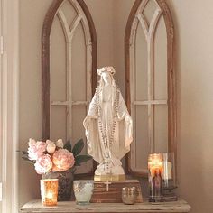 a white statue sitting on top of a table next to candles and flowers in vases