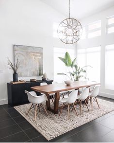 a dining room table with white chairs and a rug on the floor in front of it