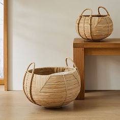 two woven baskets sitting next to each other on a wooden table with the words west elm written below them