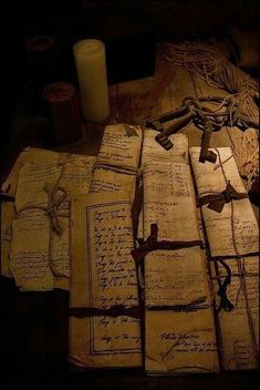 many old papers with writing on them and a candle in the middle one is lit