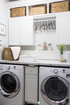 a washer and dryer in a white laundry room with baskets on the wall