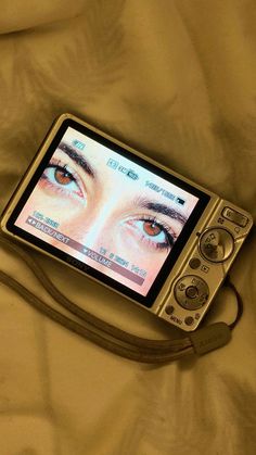 an electronic device with a woman's eye on it sitting on top of a bed