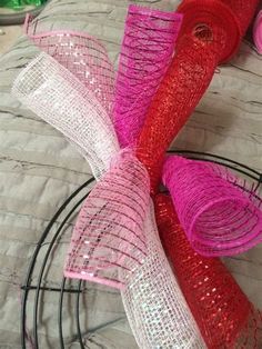 three rolls of pink and red sequinized ribbon on a bed