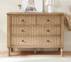 a wooden dresser with two pictures on top of it and a rug in front of it