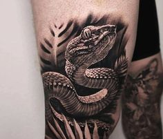 a man's arm with a snake on it and leaves around the arm, in black and white