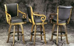 three black and gold bar stools with armrests in front of a gray background