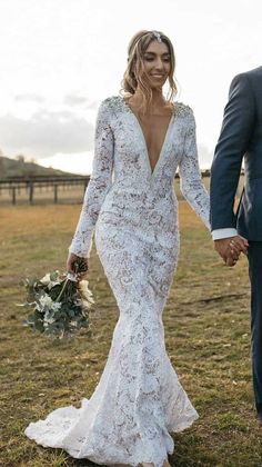 a bride and groom holding hands in the field