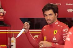 a man holding a knife in his right hand while standing next to a red car