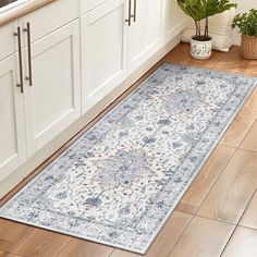 a large rug in the middle of a kitchen with white cabinets and wooden flooring