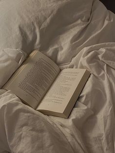 an open book laying on top of a bed