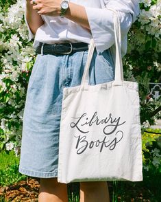 a woman holding a library book bag in her hands