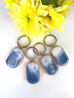 six blue and white ceramic keychains sitting next to yellow flowers