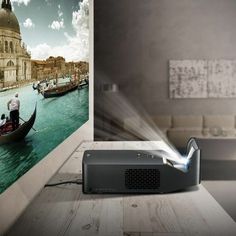 a projector sitting on top of a wooden table next to a wall with boats in the water