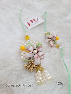 the necklace is decorated with flowers and pearls on a white furnishing area next to a tag