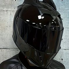 a black motorcycle helmet sitting on the back of a man's head in front of a concrete wall