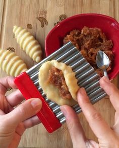 two hands are holding a metal grater over a bowl of food with sliced bananas on the side