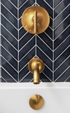 two gold faucets on the wall in a bathroom