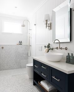 a white and black bathroom with a sink, toilet, mirror and bathtub in it