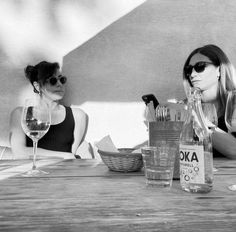 two women sitting at a table with wine glasses