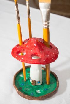 three brushes and two paintbrushes are on a small mushroom shaped stand with green grass