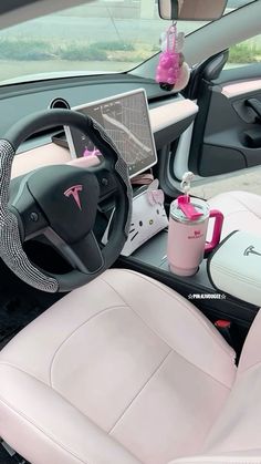 the interior of a car with pink leather seats and steering wheel, cup holder, laptop computer and other items