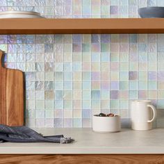 a kitchen counter with two mugs and a cutting board