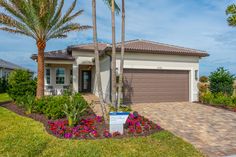 a house with palm trees and flowers in front of it